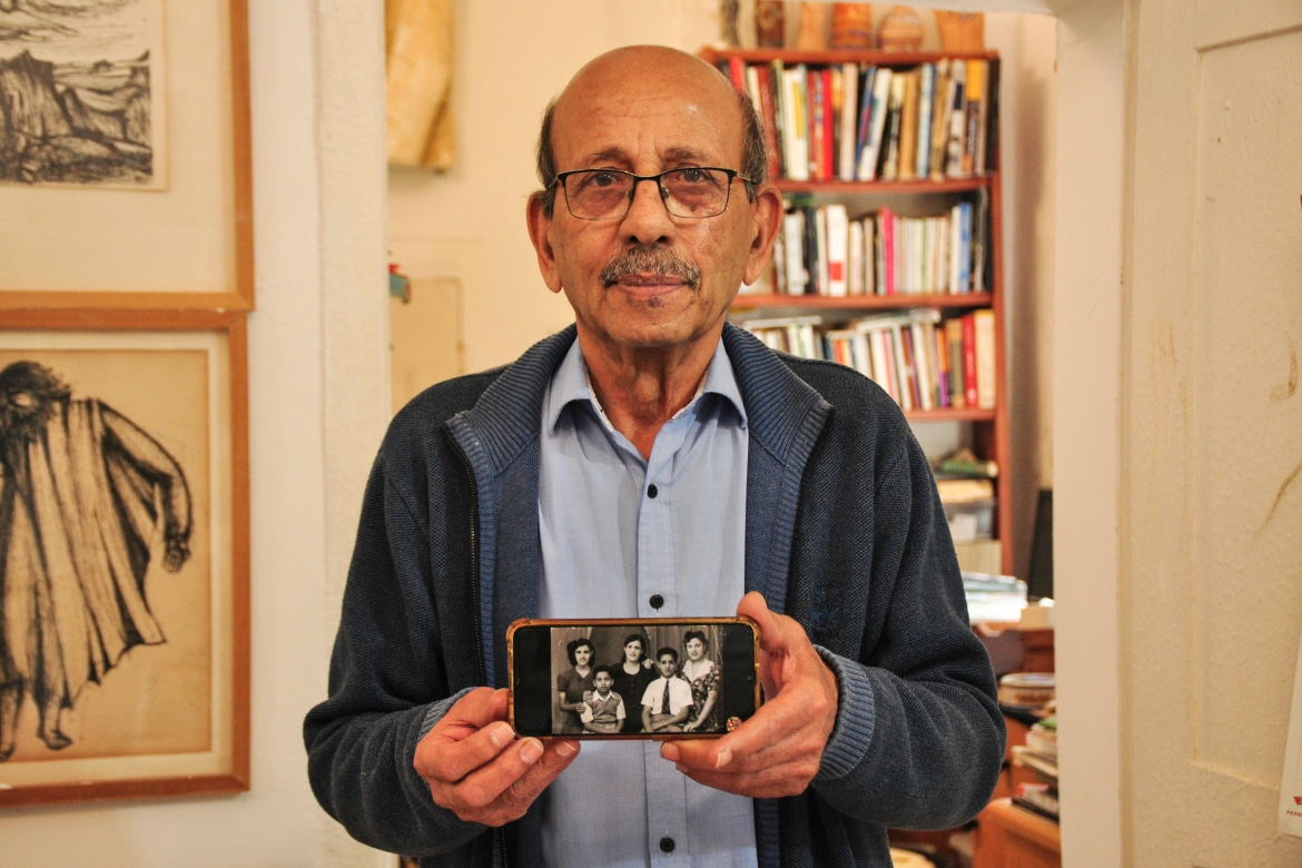Abded Abdi holding an old picture of himself with his family in 1951