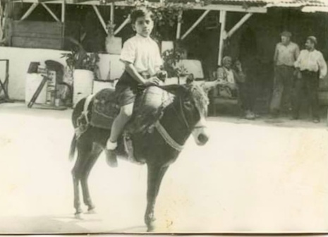 Abed Abdi sitting on a donkey at his father's "Horse taxi" business, 1953
